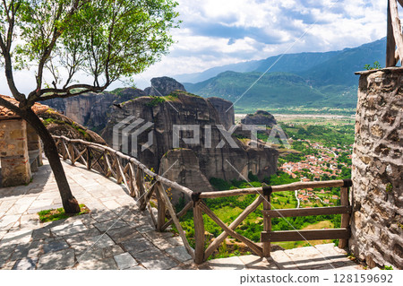Wooden fence viewpoint overlooking dramatic rock formations and valley town in Meteora Greece 128159692