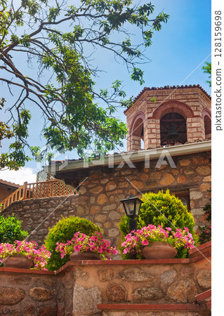 Monastery courtyard with potted flowers and bell tower in Meteora Greece 128159698