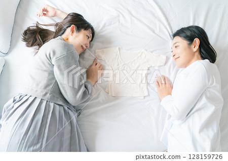 母女倆躺在床上，互相抓著內衣，熱切地等待寶寶 128159726