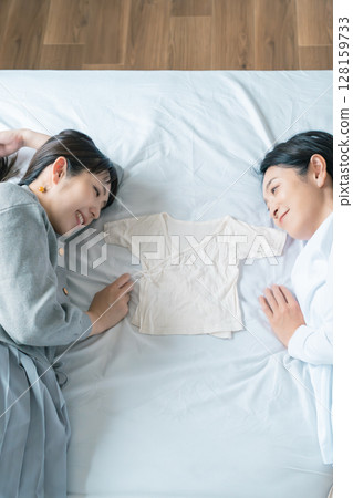 母女倆躺在床上,互相抓著內衣,熱切地等待寶寶 母女倆躺在床上,互相抓著內衣,熱切地等待寶寶 128159733