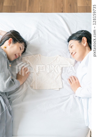 母女倆躺在床上，互相抓著內衣，熱切地等待寶寶 128159735