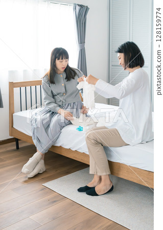Mother and daughter preparing baby's clothes in the bedroom 128159774