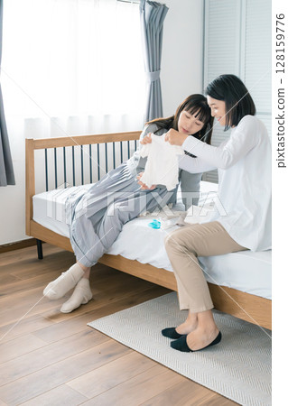 母親和女兒在臥室準備嬰兒的衣服 母親和女兒在臥室準備嬰兒的衣服 128159776