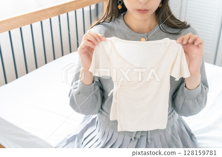 孕婦在臥室準備嬰兒衣服 128159781