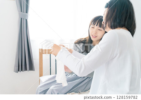 Mother and daughter preparing baby's clothes in the bedroom 128159782
