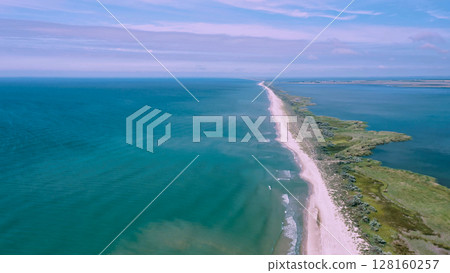 Aerial view of waves on a gritty ocean beach. Oncoming waves crashing against the sandy tropical shore over and over again. Aerial drone top view of sandy and wavy beach. 128160257
