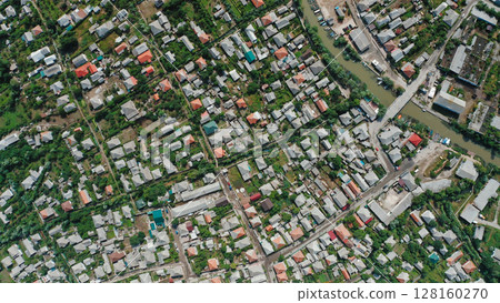 Top view of the roofs of houses of a small town with a river, bridge, cars, boats. Drone view of a small town on a summer day. Top view of the roofs of houses of a small town with a river, bridge, cars, boats. Drone view of a small town on a summer day. 128160270