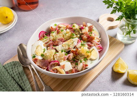Egg potato salad with bacon and fresh herbs in a plate 128160314