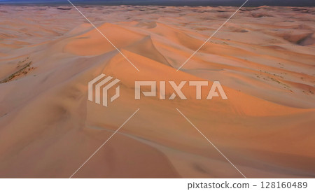 Aerial view of sand dunes in desert at sunset 128160489