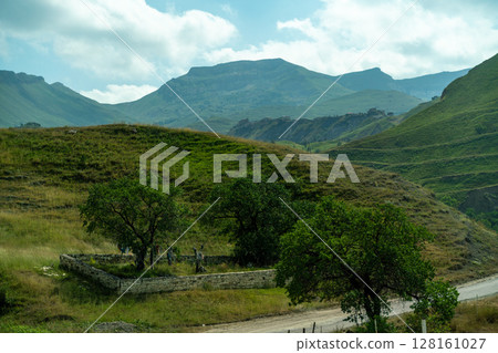 A mountain range with a small house in the middle of the field 128161027