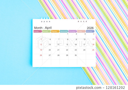 April 2026 desk calendar on blue and rainbow color background. 128161202