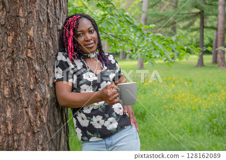 Black Woman Drinking Coffee in Nature Outdoor Relaxation 128162089