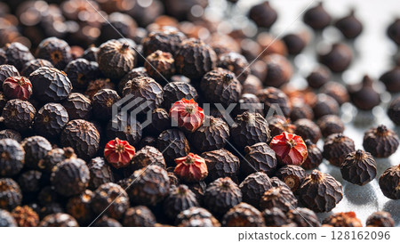 A pile of black and red pepper seeds. The red seeds are scattered throughout the pile. Concept of abundance and variety, as the different colors of the seeds create a visually interesting 128162096