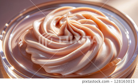 A swirl of cream is in a glass bowl. The cream is light pink and has a smooth texture. The bowl is clear and the cream is visible through the sides A swirl of cream is in a glass bowl. The cream is light pink and has a smooth texture. The bowl is clear and the cream is visible through the sides 128163015