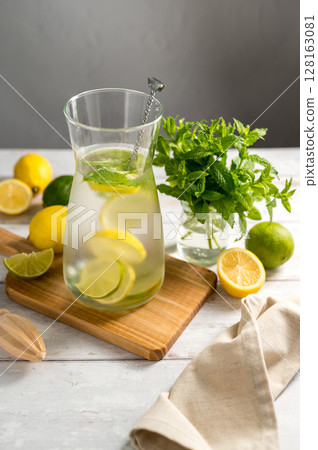 A glass jug with lemonade with lemons, limes and fresh mint, summer drink 128163081