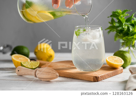 Pouring homemade lemonade drink made from lemons, limes and fresh mint. Pouring homemade lemonade drink made from lemons, limes and fresh mint. 128163126