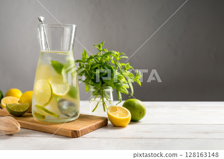 A glass jug with lemonade with lemons, limes and fresh mint, summer drink. Copy space A glass jug with lemonade with lemons, limes and fresh mint, summer drink. Copy space 128163148