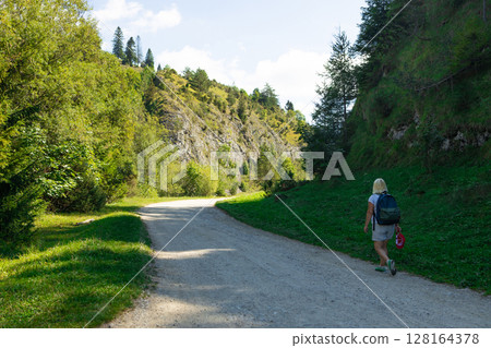 Cyclist on Scenic Gravel Path in Mountain Valley on Sunny Day Cyclist on Scenic Gravel Path in Mountain Valley on Sunny Day 128164378