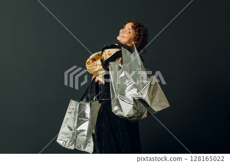 Portrait of a young adult woman dressed in a medieval dress holding shopping bags in hands Portrait of a young adult woman dressed in a medieval dress holding shopping bags in hands 128165022