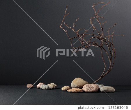 An intricately entwined branches and smooth stones against a black background. 128165046
