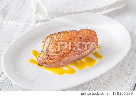 Whole Crispy Duck Breast on Mustard Lemon Honey Sauce in White Plate Whole Crispy Duck Breast on Mustard Lemon Honey Sauce in White Plate 128165189