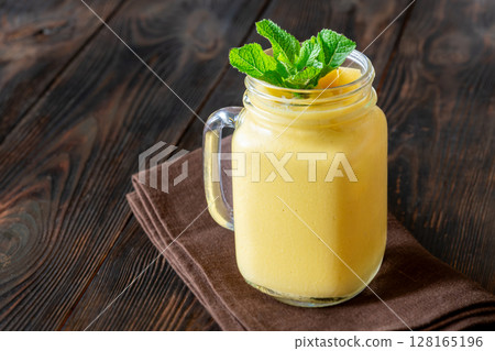 Chilled mango lassi in mason jar topped with mint and mango cubes Chilled mango lassi in mason jar topped with mint and mango cubes 128165196