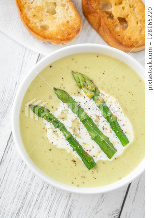 Creamy asparagus soup in white bowl with swirl and toasted ciabatta Creamy asparagus soup in white bowl with swirl and toasted ciabatta 128165220