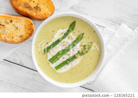 Creamy asparagus soup in white bowl with swirl and toasted ciabatta 128165221