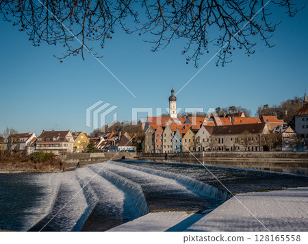 Historic Town Of Landsberg Am Lech In Bavaria: Winter Charm With A Frozen River And Colorful Houses Under A Clear Blue Sky Historic Town Of Landsberg Am Lech In Bavaria: Winter Charm With A Frozen River And Colorful Houses Under A Clear Blue Sky 128165558