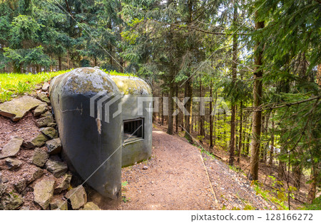 Czechoslovak border fortifications stand amidst lush green forest, showcasing historical military architecture. The structure blends with nature, highlighting its historical significance. 128166272