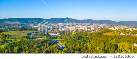 Aerial view capturing the evening glow of summer sunrise bathing the city of Liberec and the iconic Jested Mountain Ridge in warm light, with the serene landscape. Czechia 128166309