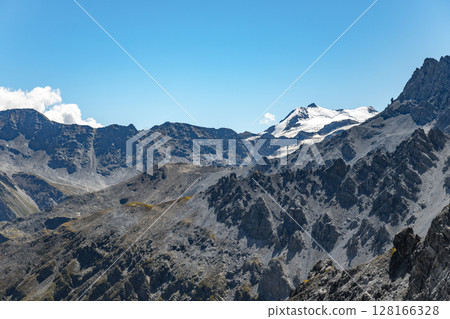 The towering Ortles Mountain stands grand under blue skies, its snowy caps and rugged terrain evincing the serene beauty of the Italian Alps. The towering Ortles Mountain stands grand under blue skies, its snowy caps and rugged terrain evincing the serene beauty of the Italian Alps. 128166328