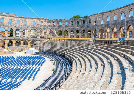 The Roman amphitheatre in Pula, Croatia, features well-preserved stone structure with seating for spectators. This historical site reflects ancient engineering and cultural significance. 128166355
