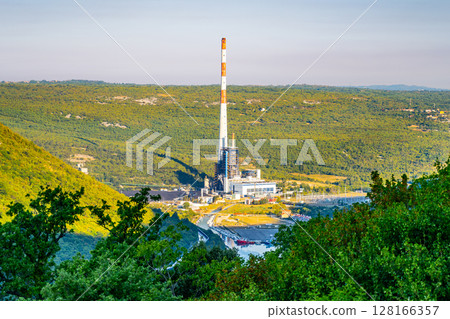 Plomin Power Station stands prominently in Istria Peninsula, surrounded by lush greenery. The facility, known for its significant energy output, showcases an industrial presence amid nature. 128166357