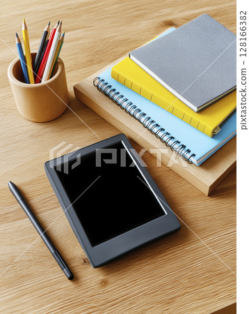 Tablet with blank screen, notebooks, and colored pencils on wooden desk for educational purposes 128166382