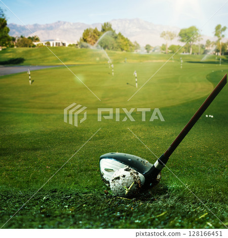 Golf club striking ball on fairway with sprinkler system and distant mountains Golf club striking ball on fairway with sprinkler system and distant mountains 128166451