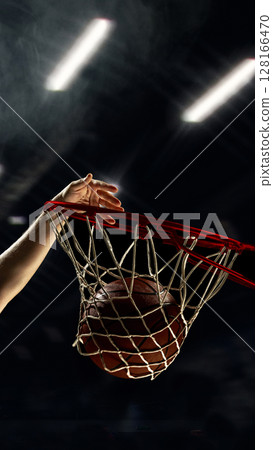 Basketball dunk with player hand pushing ball through hoop 128166470