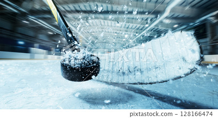 Close-up of hockey stick hitting puck on ice during fast action in indoor 3D rink Close-up of hockey stick hitting puck on ice during fast action in indoor 3D rink 128166474