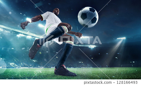 Soccer player kicking ball on 3D stadium field at night with dramatic lighting Soccer player kicking ball on 3D stadium field at night with dramatic lighting 128166493