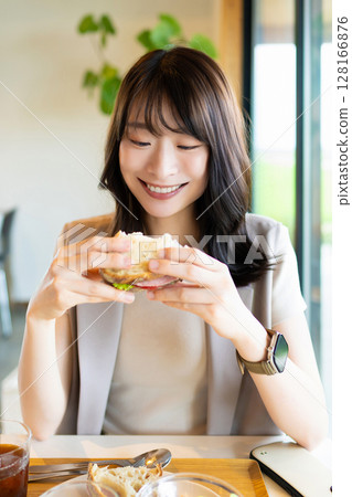 Smiling woman eating lunch at a cafe Smiling woman eating lunch at a cafe 128166876