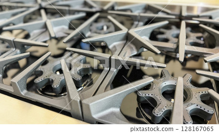 a close-up view of multiple industrial gas stove burners with cast iron grates 128167065