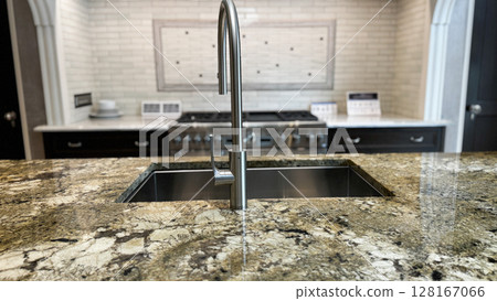 a modern kitchen island with a granite countertop and a sleek stainless steel faucet, with a stove and tiled backsplash a modern kitchen island with a granite countertop and a sleek stainless steel faucet, with a stove and tiled backsplash 128167066