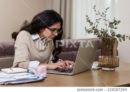 Beautiful woman in shirt using laptop while working at home 128167264