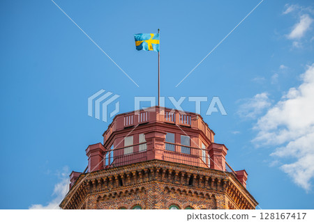 Bredablick Tower top stands tall against a clear blue sky in Skansen, with the Swedish flag fluttering at its peak. Stockholm, Sweden Bredablick Tower top stands tall against a clear blue sky in Skansen, with the Swedish flag fluttering at its peak. Stockholm, Sweden 128167417