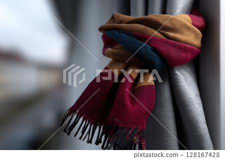 Cozy scarf hanging by the window on a cloudy day in a warm living space 128167428
