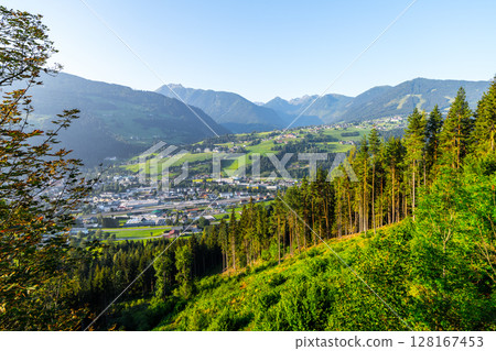 Early morning light illuminates the picturesque landscape of Schladming in Low Tauern, Austria, showcasing lush green hills and valleys under a clear blue sky. Early morning light illuminates the picturesque landscape of Schladming in Low Tauern, Austria, showcasing lush green hills and valleys under a clear blue sky. 128167453