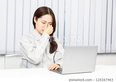 Asian woman in work clothes holding her eyes 03 Asian woman in work clothes holding her eyes 03 128167463