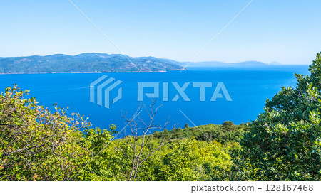 Overlooking the vibrant blue waters of the Adriatic Sea, the view from Istria Peninsula captures a breathtaking landscape. Lush greenery frames this serene coastal scene. Overlooking the vibrant blue waters of the Adriatic Sea, the view from Istria Peninsula captures a breathtaking landscape. Lush greenery frames this serene coastal scene. 128167468