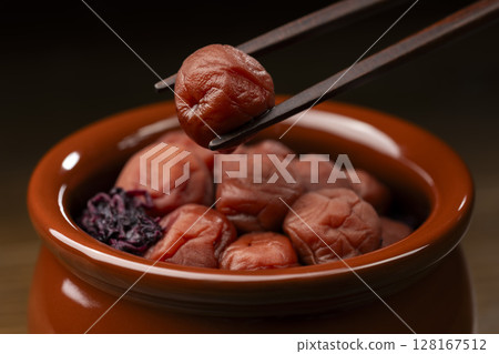 用筷子夾起一罐醃梅子 用筷子夾起一罐醃梅子 128167512