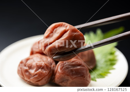 黑色背景中用筷子夾起的李子 黑色背景中用筷子夾起的李子 128167525